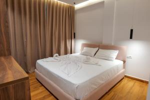 Un dormitorio con una cama blanca con toallas. en Hotel Havana, en Sarandë