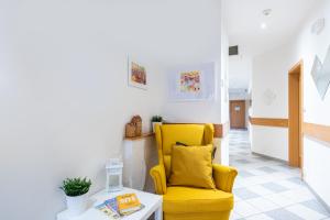 una sedia gialla in un soggiorno con tavolo di Libero Residence a Praga