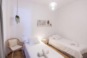 een witte kamer met 2 bedden en een stoel bij Precioso apartamento en Lanzarote, zona Arrecife - El Charco de San Ginés in Arrecife