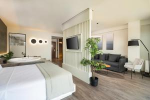 1 dormitorio con 1 cama, TV y sofá en Heaven Hotel Thessaloniki Airport, en Néon Rýsion