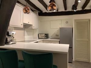 a kitchen with white cabinets and a refrigerator at Historic Grade II Listed Homely Cottage in Stamford