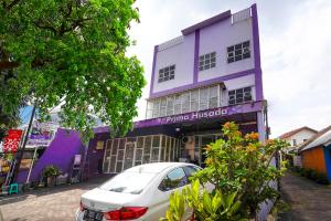OYO 91299 Violet Guest House في باندونغ: مبنى ارجواني مع سيارة متوقفة أمامه