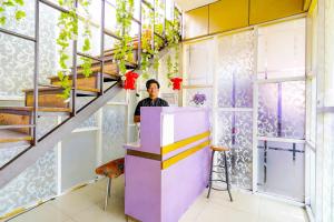 Un uomo in piedi dietro un bancone in una stanza con le scale di OYO 91299 Violet Guest House a Bandung