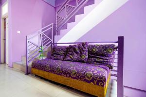 um sofá roxo num quarto com uma escada em OYO 91299 Violet Guest House em Bandung