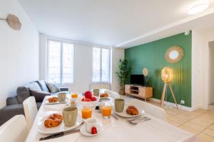 una sala de estar con una mesa con comida. en Appart'Hotel NuiteeJour Versailles Saint Cyr l'Ecole, en Saint-Cyr-lʼÉcole