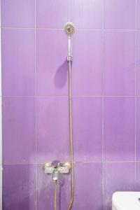 e bagno piastrellato viola con doccia e servizi igienici. di OYO 91299 Violet Guest House a Bandung