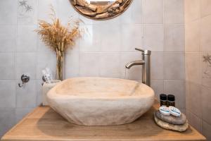 a bathroom with a large stone tub on a wooden counter at Kanelis Milos Sea Suite in Agia Irini Milos