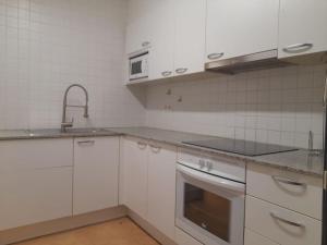 a kitchen with white cabinets and a sink and an oven at Apartamento Brava in Palafrugell
