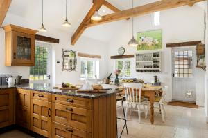 a kitchen with wooden cabinets and a table with chairs at Blenheim Cottage, Beautiful 15th Century Cotswold Cottage, 4 Bed, Nr Chipping Campden in Mickleton