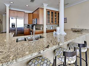 a kitchen with a granite counter top with two bar stools at Beach Club #1605C in Pensacola Beach +54 photos