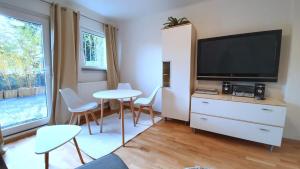 a living room with a television and a table and chairs at City Apartment Hanau in Hanau am Main