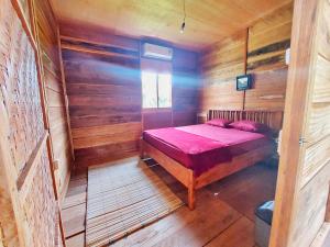 a bedroom with a bed in a wooden cabin at Sunset Cottage in Telaga