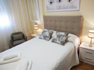 sypialnia z dużym białym łóżkiem i krzesłem w obiekcie O AREAL DE NATALIA w mieście Muxia