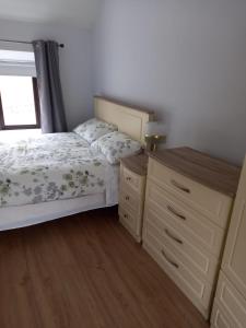 a bedroom with a bed and a dresser and a window at Jack's House in Glenties