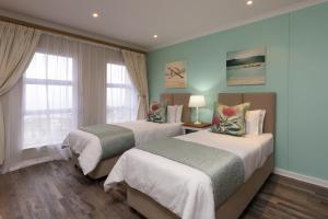 duas camas num quarto com duas janelas em Pinnacle Point 2-bedroom self-catering apartment em Mossel Bay