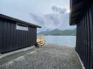 Fagervik Camping في Tresfjord: مبنى أسود بجوار تجمع للمياه