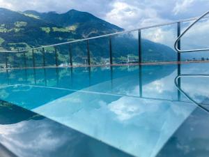 ein Glasgebäude mit einer Reflexion im Wasser in der Unterkunft Hotel Malerhaus in Fügen