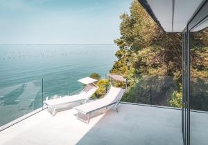 two white chairs on a balcony overlooking the water at Seaside Resort in Trieste