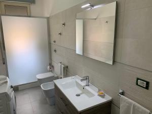 bagno con lavandino, servizi igienici e specchio di Dimoramare a Tonnara di Bonagia