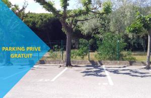 a tennis court with a tree in the middle at MES VACANCES A LA MER studio 4 pers, parking privé, wifi, linges fournis, climatisation in La Grande Motte