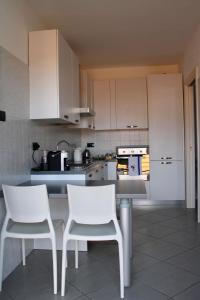 uma cozinha com armários brancos e cadeiras brancas em Rho Fiera Milano - Popy House em Pero