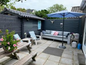 eine Terrasse mit einem Sofa, einem Sonnenschirm und Stühlen in der Unterkunft Appelbloesem in Bergen