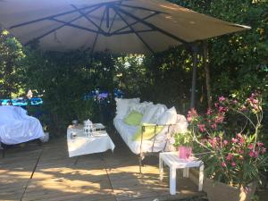 a couch and a table under an umbrella at Le Havre de paix in Saint-Cyr-sur-Loire