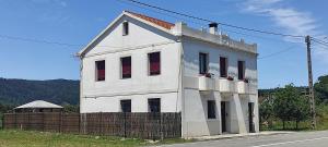 ein weißes Gebäude mit roten Rollläden auf einer Straße in der Unterkunft CRAFT HOME Ponteceso Camiño dos Faros in Ponteceso