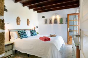 a bedroom with a white bed with red towels on it at La Casa del Medianero in Mácher