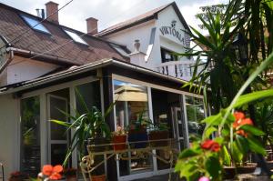 uma casa de hóspedes com portas de vidro e plantas em Hotel Viktória em Balatonalmádi
