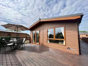 a wooden deck with a table and an umbrella at Buttercup Lodge With Hot Tub in Little Habton