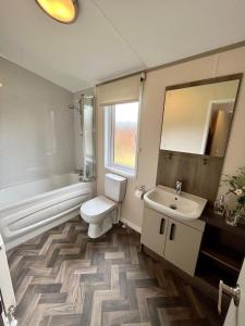 a bathroom with a sink and a toilet and a mirror at Buttercup Lodge With Hot Tub in Little Habton
