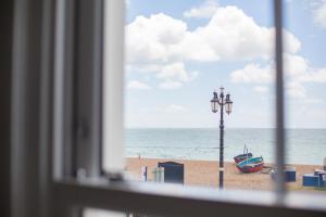 ein Fenster mit Blick auf den Strand mit einem Boot und einer Straßenbeleuchtung in der Unterkunft Lovely 3-Bedroom Apartment with Stunning Sea Views in Worthing