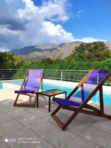 2 sillas y una mesa junto a la piscina en Cabaña Negusa en Merlo