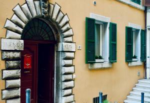 a building with green shuttered windows and a door at Il Mono del Porto - Studio Apartment in Ancona