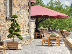 a patio with tables and chairs and a red umbrella at Schloss Hotel Burgbrohl in Burgbrohl