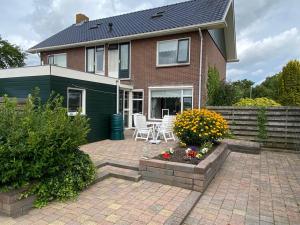 a house with a patio with chairs and flowers at Woning aan het water in het Friese Merengebied in Jutrijp