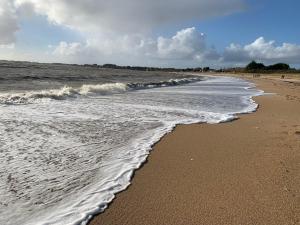 a sandy beach with waves coming in from the ocean at Charmante maison de ville dans un bourg typique in Noyal-Muzillac