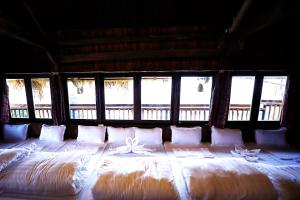 a large bed with pillows in a room with windows at Không gian văn hóa trà Suối Giàng in Văn Chấn