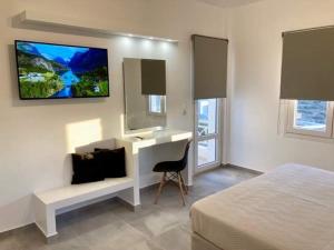 a bedroom with a desk and a tv on the wall at IosAgnanti in Ios Chora