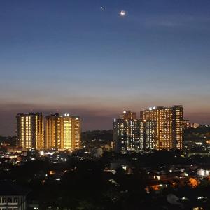 une ligne d'horizon avec de grands bâtiments la nuit dans l'établissement 1010 - Bohemian Apartment, à Bandung