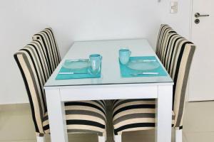 una mesa blanca con 2 sillas y una mesa con platos en Departamento con pileta, parilla y gym en Recoleta - Piso 7 en Buenos Aires