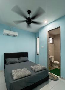 1 dormitorio con pared azul y ventilador de techo en FAIZ HOMESTAY, en Kuching