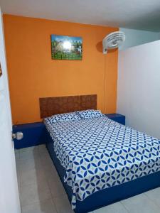 een slaapkamer met een blauw en wit bed met een oranje muur bij HOTEL CASA XION in Neiva