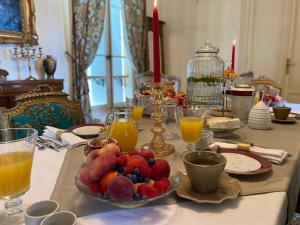 a table with a bowl of fruit and glasses of orange juice at Château Bois-Martin in Léognan