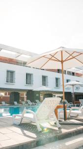 un grupo de sillas y una sombrilla junto a una piscina en Hotel Real Ica, en Ica