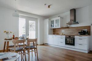 a kitchen with white cabinets and a table and chairs at Auszeit Neusiedlersee in Mörbisch am See
