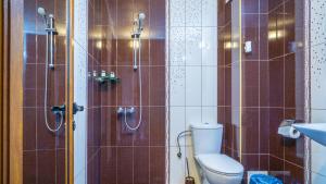 a bathroom with a toilet and a shower with brown tiles at Guest House Karamihalevi in Sozopol +63 photos