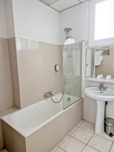 a bathroom with a bath tub and a sink at Hôtel P.L.M. in Cannes