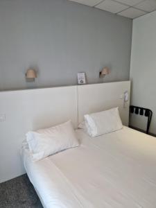 a white bed with two pillows on top of it at Hôtel P.L.M. in Cannes